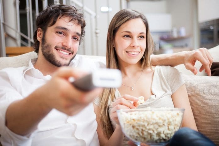 couple watching tv together with popcorn bowl on couch