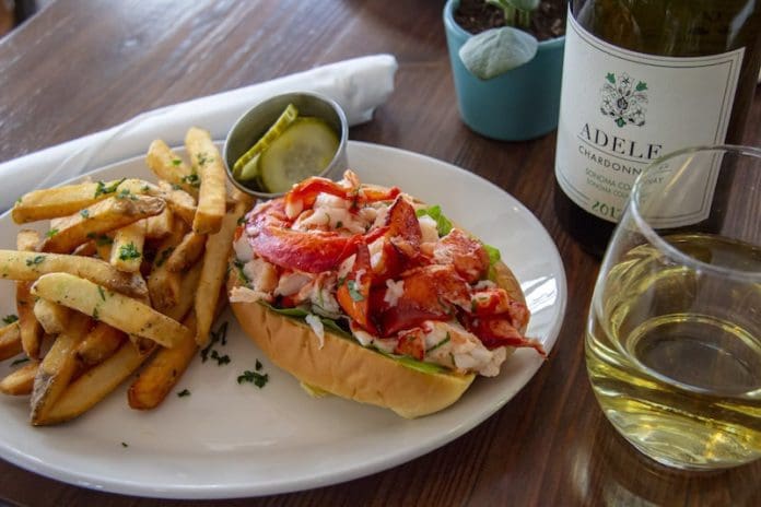lobster roll on a plate with fries and wine green hill kitchen greenport
