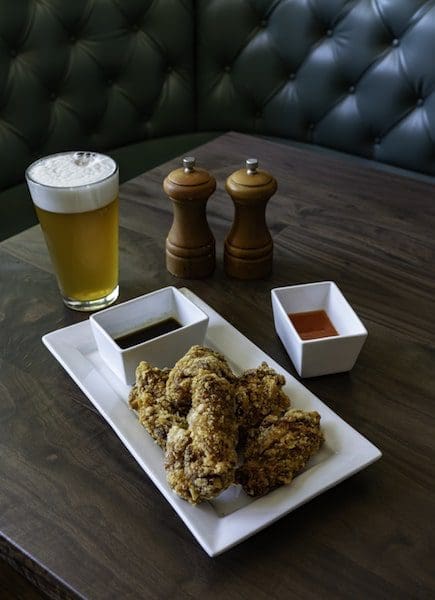 crispy wings and beer on table in rustic tavern salt and pepper shakers