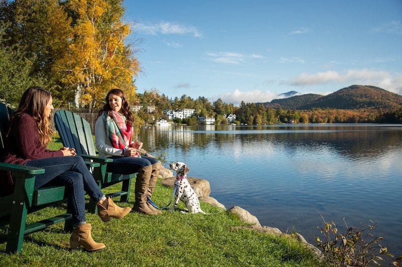lake placid fall lake with puppy and two people sitting in adirondack chairs