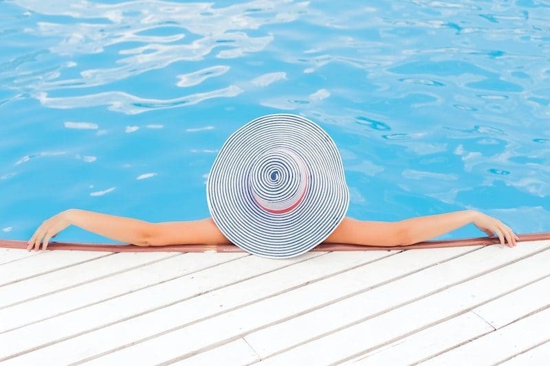 woman lounging by the pool with hat