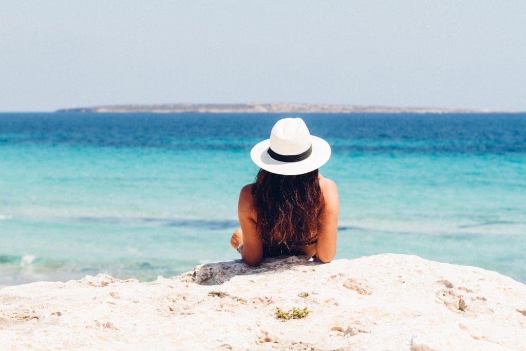 Woman on beach with white hat sand