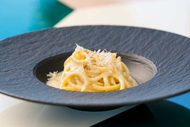 spaghetti carbonara in a black plated neat dish