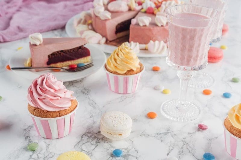 Close up of pink cake, marshmallows, candies, sweet cupcakes