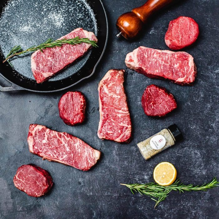 steaks on a black background pepper rosemary salt