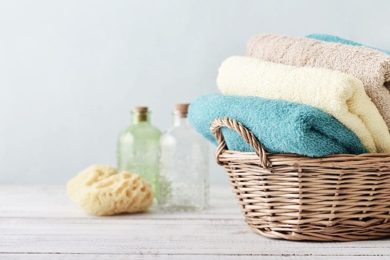 soft bath towels in basket with sponge