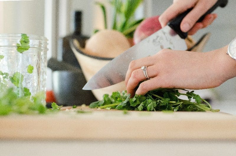 woman cooking and cutting with knife on cutting board