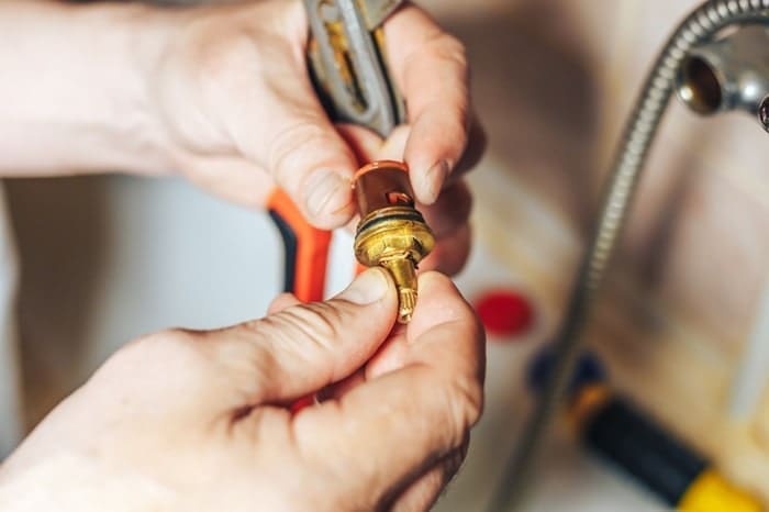 Man repair and fixing leaky old faucet in bathroom