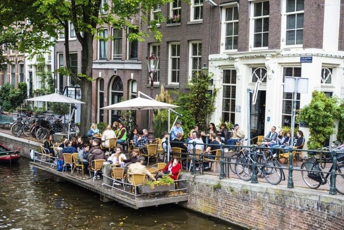 People on a floating terrace bar drinking along of a canal in Amsterdam Netherlands