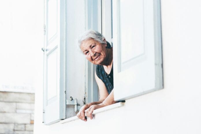 elderly woman leaning out window smiling