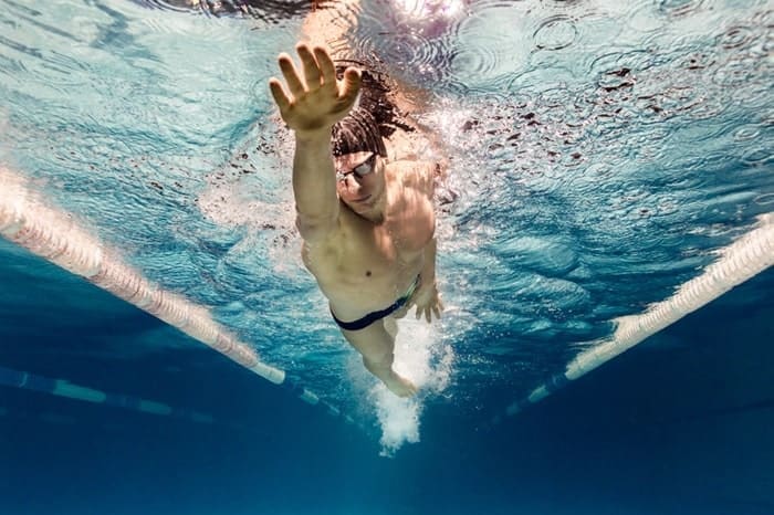 Underwater picture of young swimmer in goggles exercising