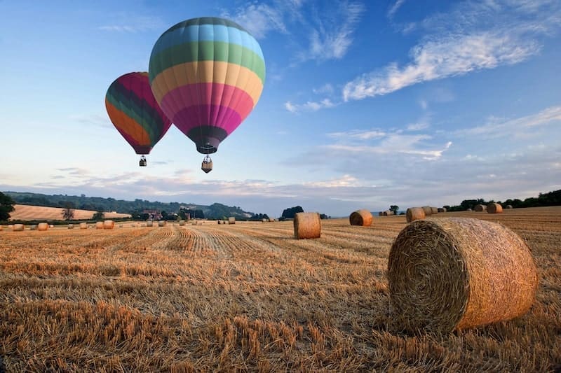 Hot air balloons over hay bales sunset landscape