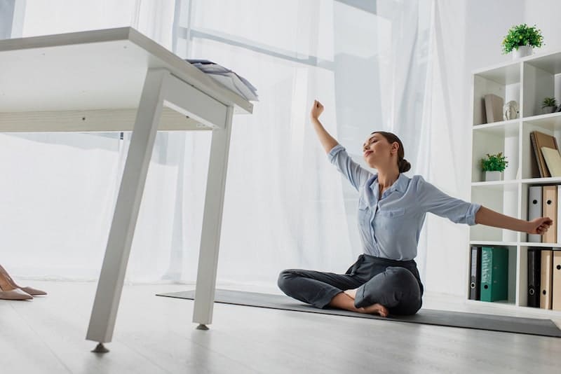 Young businesswoman stretching hands and practicing yoga