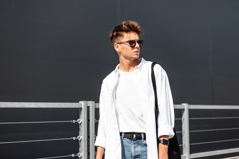 Fashionable young hipster man in stylish white clothes in blue