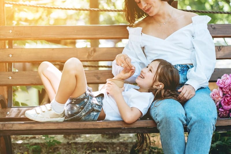 Mom feeds her little daughter ice cream in the park